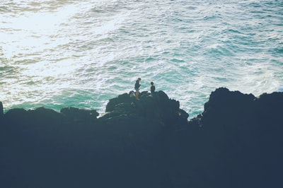 两个人站在海边的悬崖上